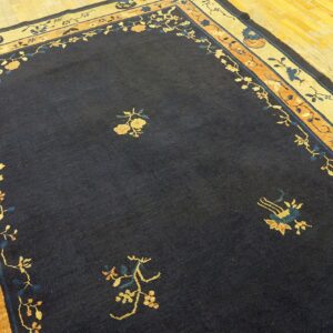 Navy area rug featuring sparse yellow floral details and elaborate multicolored borders on hardwood flooring.