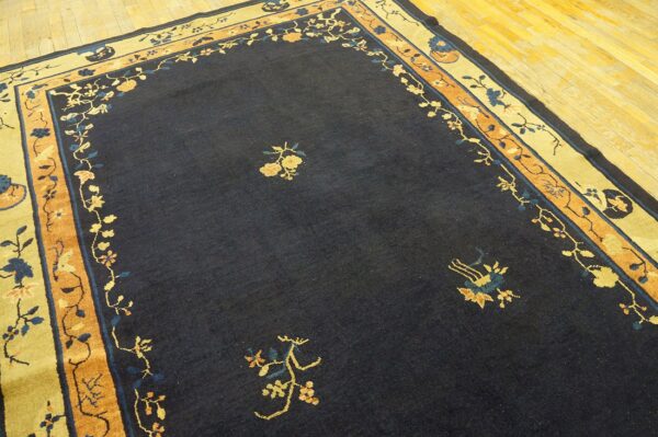 Navy area rug featuring sparse yellow floral details and elaborate multicolored borders on hardwood flooring.