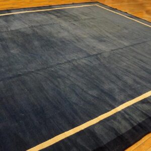 Navy blue rug with a light tan inner border stripe lies on polished hardwood floor.