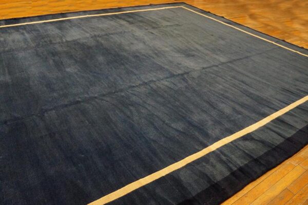 Navy blue rug with a light tan inner border stripe lies on polished hardwood floor.