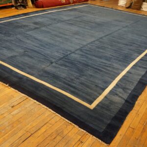 Blue rug with color striations featuring a contrasting cream and navy blue bordered edge on wood flooring.