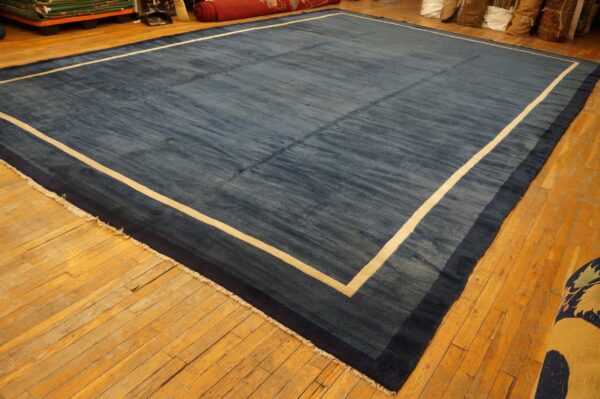 Blue rug with color striations featuring a contrasting cream and navy blue bordered edge on wood flooring.