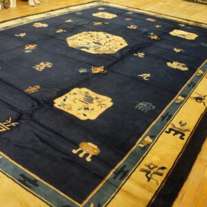 Large indigo rug with stylized medallions and symbols has a wide gold border on wood flooring.