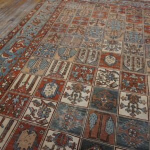 Rust and blue rug with a geometric grid pattern lies on light-colored distressed wood floorboards.