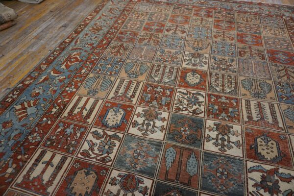 Rust and blue rug with a geometric grid pattern lies on light-colored distressed wood floorboards.
