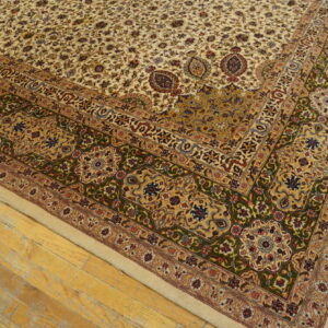 Low-pile rug with a cream ground, dense floral pattern, and thick green and gold border on wooden flooring.