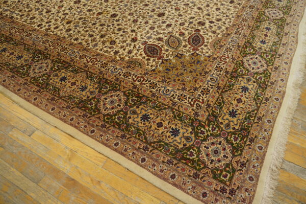 Low-pile rug with a cream ground, dense floral pattern, and thick green and gold border on wooden flooring.