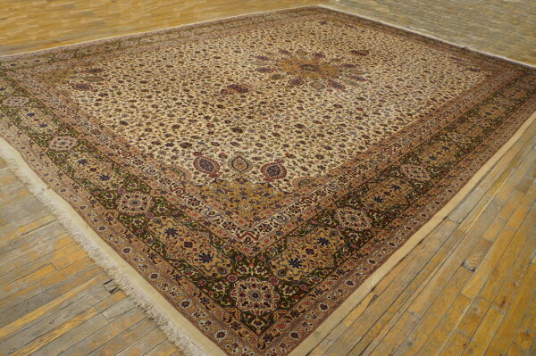 A large square rug with a cream floral pattern and dark green and gold detailed borders on wood flooring.