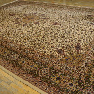 Large cream rug with a dense floral design, gold medallion, and wide olive green border on wood floors.