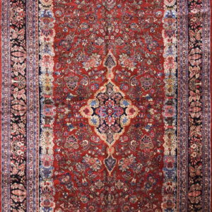 Red traditional low-pile rug featuring a dense floral pattern, a central medallion, and navy and black borders.