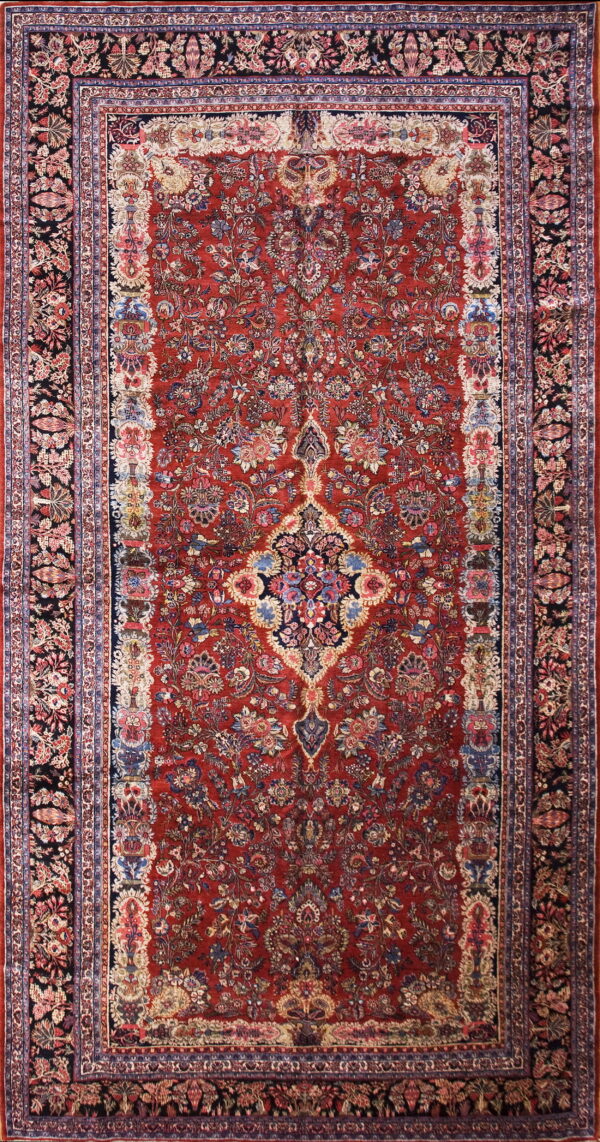 Red traditional low-pile rug featuring a dense floral pattern, a central medallion, and navy and black borders.