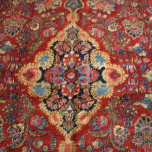 Traditional rug featuring a dense blue and cream floral pattern across a vibrant, low-pile red field.