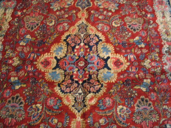 Traditional rug featuring a dense blue and cream floral pattern across a vibrant, low-pile red field.