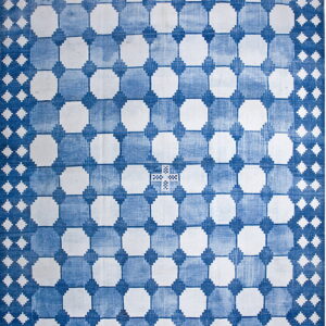 A low-pile blue and white rug displays a faded geometric grid pattern with large white shapes.
