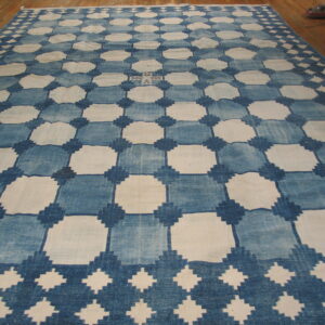 Large blue and white checkerboard rug with a geometric diamond lattice pattern laid on a wood floor.