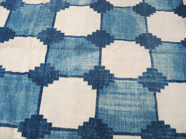 Blue and white flatweave rug displaying a geometric grid pattern with stepped cross intersections.
