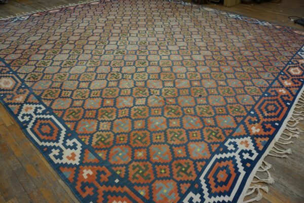 Geometric flat-weave rug with rust, navy, and teal colors covers aged wooden plank flooring.
