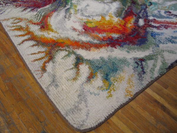 Textured white rug with abstract bursts of red, yellow, and blue colors sits on hardwood flooring.