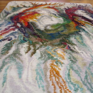 Multicolor abstract rug with high shag pile and dense swirling colors over a wood floor.