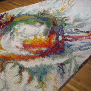 White shaggy rug featuring abstract swirls of red, orange, blue, and green on wood flooring.