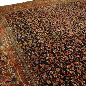 Navy area rug featuring intricate orange and multicolored floral vines, framed by a wide terracotta border.