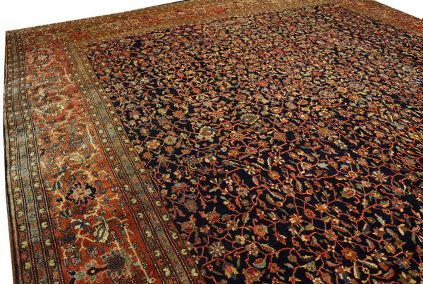 Navy area rug featuring intricate orange and multicolored floral vines, framed by a wide terracotta border.