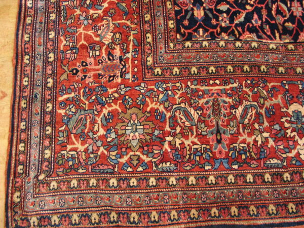 A corner section of a red and blue rug showing complex floral motifs and intricate multi-layered borders.