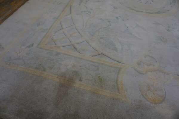 Pale blue patterned rug border with yellow trellis lines, subtle floral elements, and dark wood flooring visible.