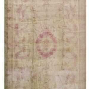 Muted, distressed rug featuring a classical floral pattern in pale rose pink and dusty beige colors.