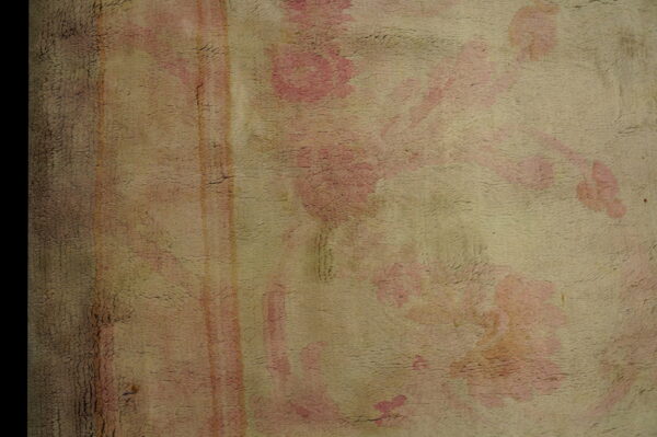 Distressed, textured rug pile featuring muted pink floral shapes and faded vertical stripes on a beige ground.