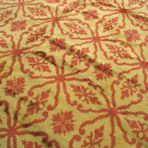 Repeating geometric medallions in rust red against a gold, textured, low-pile background.