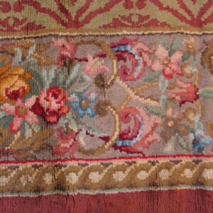Close-up of a high-pile rug border featuring floral patterns in muted colors like pink, blue, sage, gold, and red.