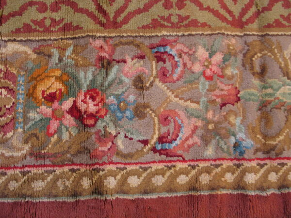 Close-up of a high-pile rug border featuring floral patterns in muted colors like pink, blue, sage, gold, and red.