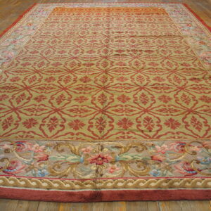 Low-pile olive green and red rug featuring a trellis field and wide floral border on wood floors.