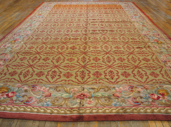 Low-pile olive green and red rug featuring a trellis field and wide floral border on wood floors.