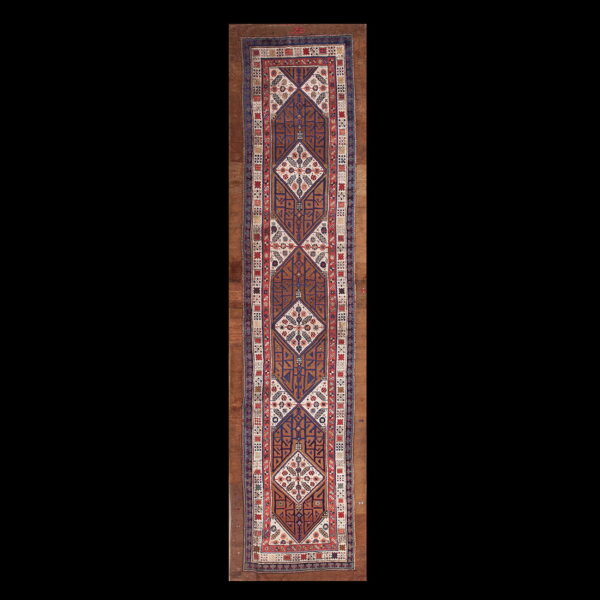 Traditional runner rug featuring interlocking brown, navy, red, and cream geometric diamond patterns.