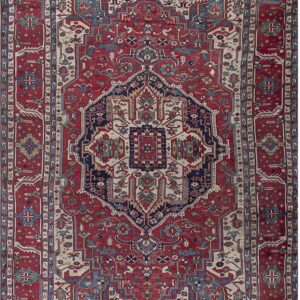 Traditional red rug with a central medallion and detailed geometric motifs in navy, teal, and beige.