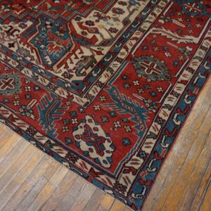 Geometric red and blue rug section featuring stylized motifs rests on rustic, worn hardwood planks.