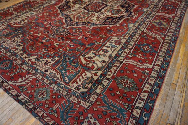 Red rug with detailed blue and cream geometric patterns partially covers worn wooden flooring.