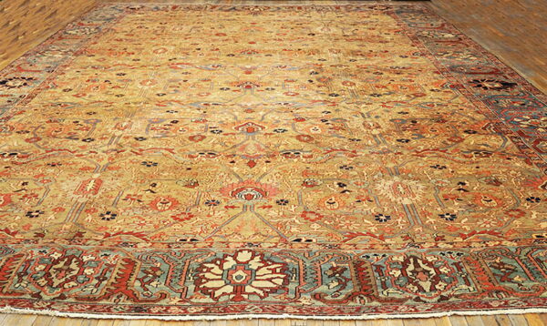 Gold field rug featuring intricate red, rust, and teal traditional patterns on hardwood flooring.