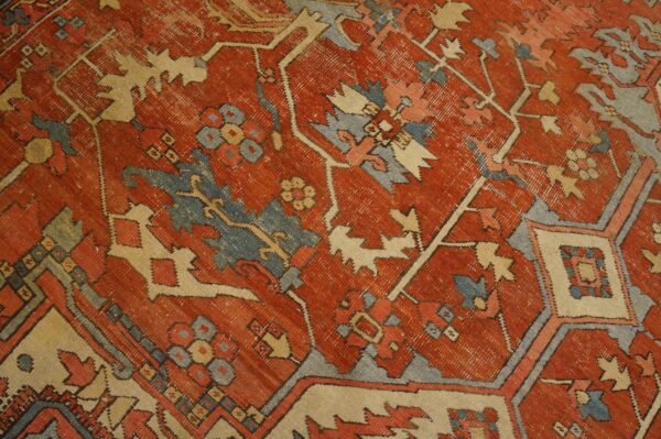 Worn rust rug texture showing blue, cream, and red geometric and stylized floral patterns.