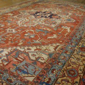 Terracotta, blue, and beige traditional rug with geometric medallion design on hardwood floor.
