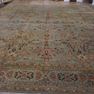 Low-pile traditional area rug with a detailed gray-blue and rust floral pattern on wood floorboards.