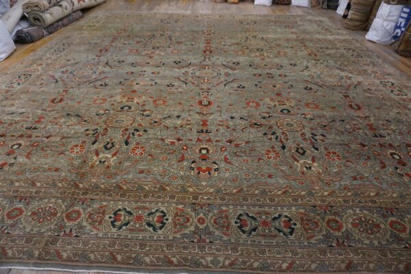 Low-pile traditional area rug with a detailed gray-blue and rust floral pattern on wood floorboards.