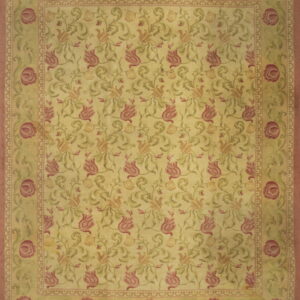 Yellow area rug with repeating pink and green floral vine pattern and wide rose-colored outer borders.