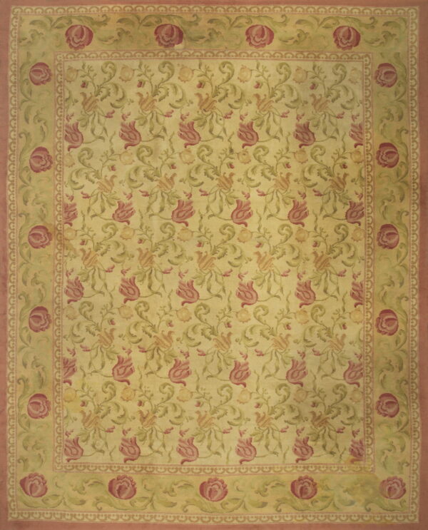 Yellow area rug with repeating pink and green floral vine pattern and wide rose-colored outer borders.
