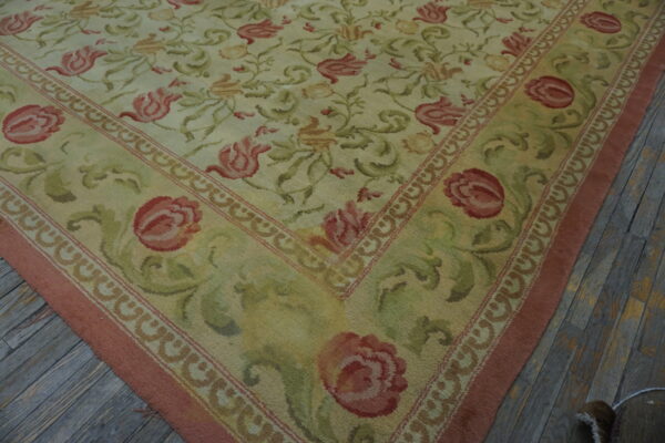 Light yellow rug with large rose and green floral patterns sits on gray distressed wooden planks.