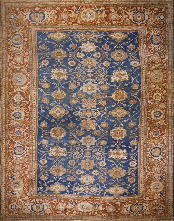 Intricate blue rug featuring tan floral designs and a wide, densely patterned rust-colored border.