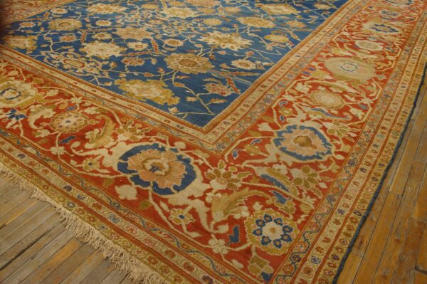 Ornate blue and red patterned rug with gold and cream motifs laying on distressed wood flooring.