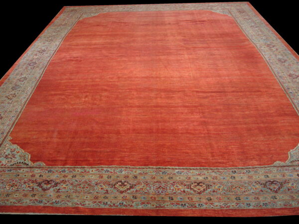 Rust-colored area rug with a simple field and traditional blue and gold detailed border.